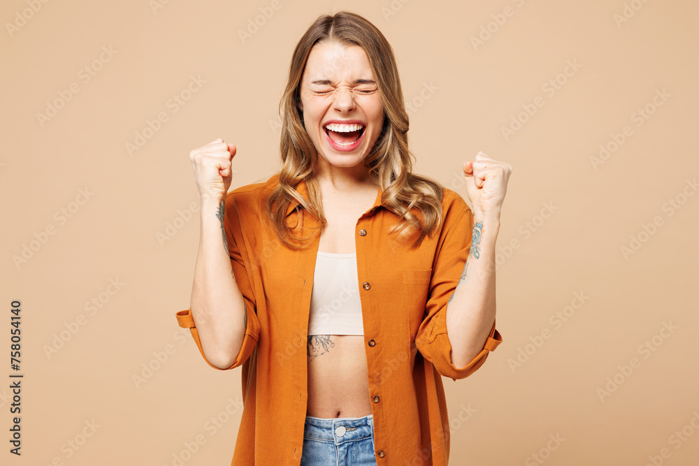 Wall mural young caucasian woman she wears orange shirt casual clothes doing winner gesture celebrate clenching