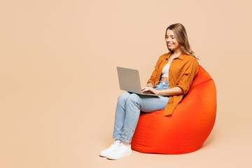 Full body young IT woman she wears orange shirt casual clothes hold use work on laptop pc computer...