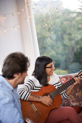 Couple, woman and play guitar in living room for men, chilling and enjoying together on couch. Married, wife and husband with smile on sofa to bond, entertainment and listen to musical instrument - obrazy, fototapety, plakaty