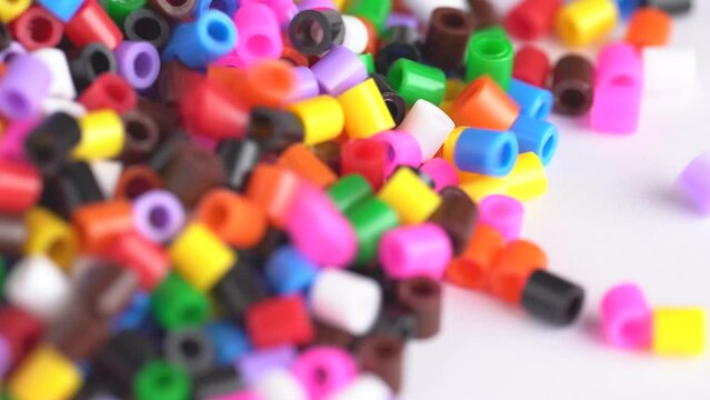 Multicolored beads falling down on white table. Colorful beads background, close up.