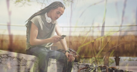 Image of grass over biracial man using smartphone