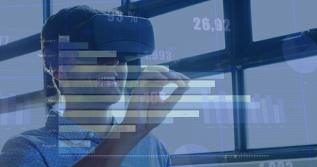 Image of numbers and statistics over caucasian man wearing vr headset