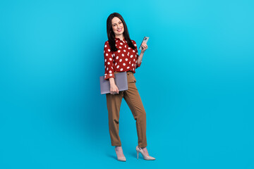 Full size photo of intelligent person wear red blouse brown trousers hold laptop smartphone at office isolated on blue color background