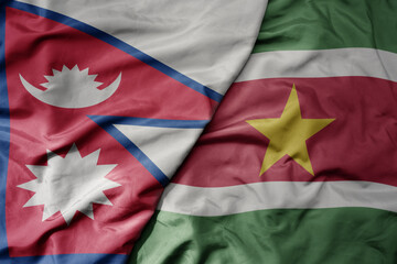 big waving national colorful flag of suriname and national flag of nepal .