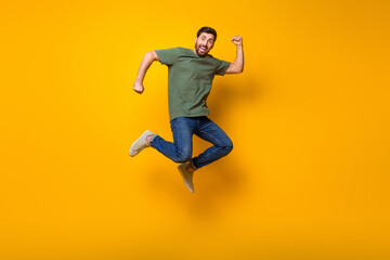 Fototapeta na wymiar Full body photo of attractive young man jump raise fist winning lottery wear trendy khaki clothes isolated on yellow color background