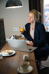 Business lady daydreaming at laptop in hotel room over lunch