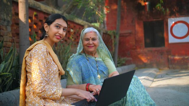 An old lady and her daughter using laptop together - technology in rural area  insurance agent  government schemes  nari shakti. Old Indian woman learning to do online shopping - educated village g...
