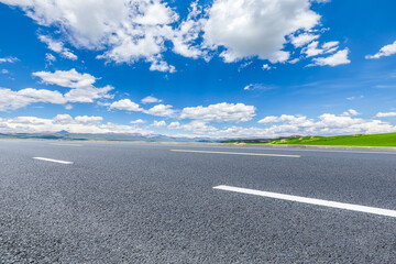 Asphalt highway road and green mountains with sky clouds background