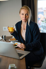 Female entrepreneur having lunch in front of laptop in room