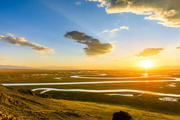 Curved river and grassland with beautiful sky clouds natural landscape at sunset in Xinjiang