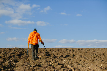 A man with an electronic metal detector in the field. Copyspace