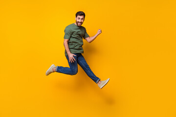 Fototapeta na wymiar Full body photo of attractive young man jump raise fist celebrate winning wear trendy khaki clothes isolated on yellow color background