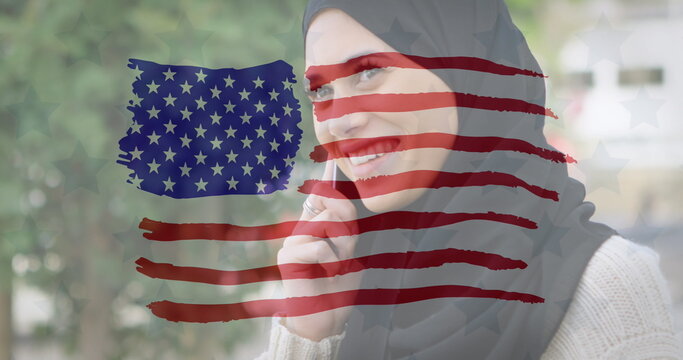 Image of American flag drawn over biracial woman in hijab talking on her smartphone in the backgroun - Powered by Adobe