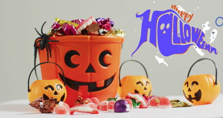 Obraz premium Happy halloween text banner and ghosts icons against pumpkin shaped bucket full of halloween candies