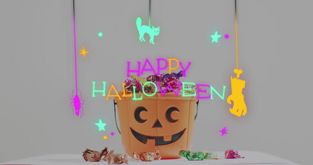 Obraz premium Neon happy halloween text banner against pumpkin shaped bucket full of halloween candies