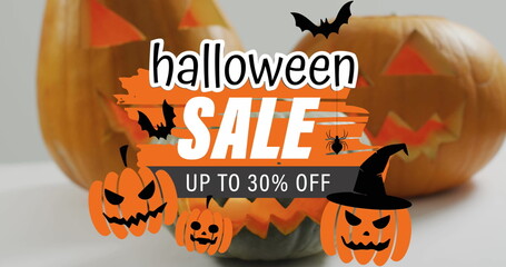 Fototapeta premium Image of halloween sale text with ghosts over orange carved pumpkins