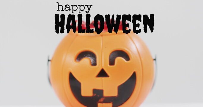 Naklejki Neon trick or treat text banner against pumpkin shaped bucket full of halloween candies