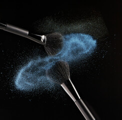 Makeup brushes colliding on black background