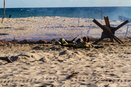 Historical reconstruction. An American infantry soldiers from the World War II  fighting on the beach between smoke and dust.