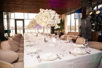 Serving the festive table at a wedding event. Decorating the wedding table with bouquets of flowers. Cutlery at a party