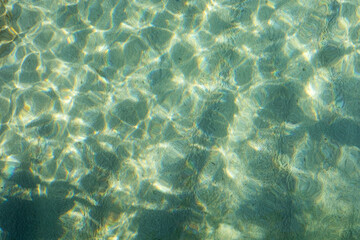 Sunlight dances on the clear water of the sea, creating a beautiful sparkle.