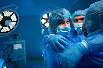 Successful surgical team hugging in surgery theater