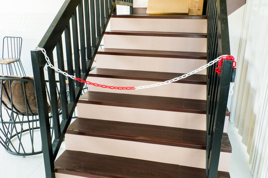 Plastic red and white warning chain links and wooden stair.