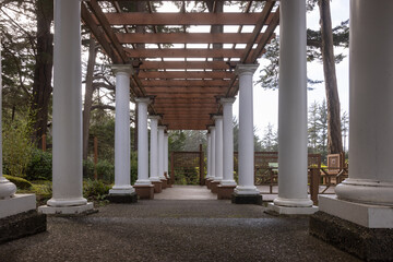 A long walkway with white pillars and a wooden roof - Powered by Adobe
