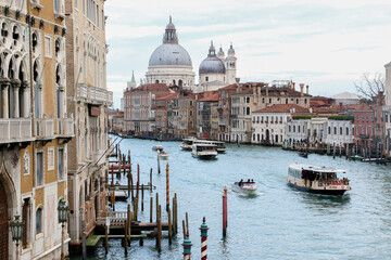 Iconic View of the Grand Canal and the Basilica Santa Maria della Salute in Venice as boats and water buses cross the canal on an overcast day - Venice, Italy