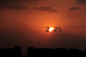 The year 2025 on the city at sunrise. Happy New Year 2025 anniversary. 2025 concept image with text on sun rising sky. Beautiful sunrise or sunset over the city silhouette