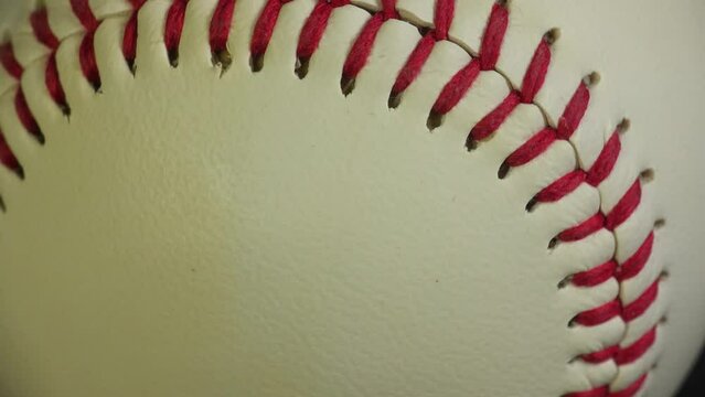 Sports and games. Close up of a rotating white leather baseball with red stitching.