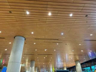 The ceiling of a building is made of wood and has many lights