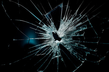 The bullet broke the window glass with a large hole and cracks on a black background.