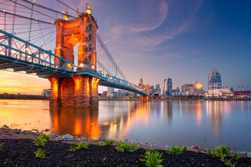 Cincinnati, Ohio, USA. Cityscape image of Cincinnati, Ohio, USA downtown skyline with the John A. Roebling Suspension Bridge and reflection of the city in the Ohio River at spring sunset.