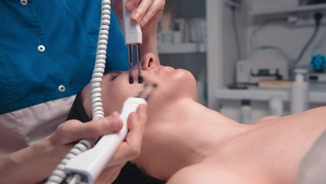 Close-up portrait of a beautiful woman with closed eyes and a skin rejuvenation machine. Salon procedures. Microcurrent therapy
