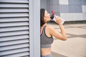 Lady resting after active exercises outside, drinking milkshake