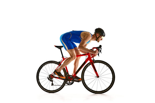 Concentrated and motivated man in sportswear and helmet, bicyclist in motion, training isolated on white studio background. Concept of sport, active and healthy lifestyle, speed, endurance, hobby