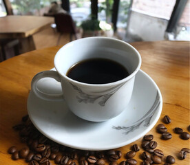 Cup with coffee on wooden table with roasted coffee beans
