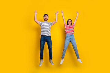 Full length photo of funky cute couple wear striped t-shirt raising hands up announcing sale...