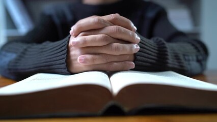 Close up hands praying on Bible at wooden table in morning, Christian concept, zooming the camera out, away from hands