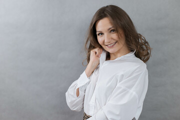 Close-up portrait of a young beautiful girl in a white shirt on a gray background, copy space