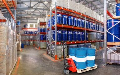 Industrial Warehouse Interior with Chemical Drums on Pallets and Hand Truck