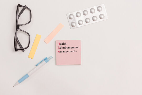Office scene with sticky note  with text "Health Reimbursement Arrangement" neatly placed on a desk