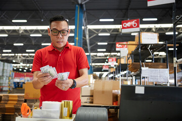 factory worker or warehouser counting money in the warehouse storage - Powered by Adobe