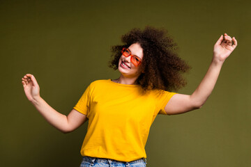 Portrait of curly hair young woman in yellow t shirt raised arms up enjoying spend summer...