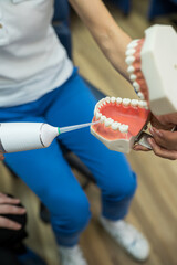 An oral health professional teaches dental hygiene techniques using an electric brush on a dental...