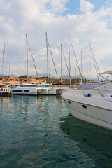 Obraz premium Double cruising catamarans and yachts in the marina. Portorosa pier in Tonnarella, Sicily. Sailboats on the water surface against the blue cloudy sky in Italy