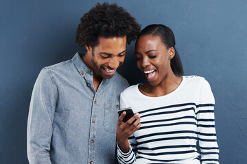 Black couple, funny and smartphone with meme, smile and social media on a blue studio background....