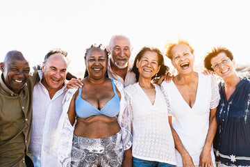Happy multiracial senior friends having fun smiling into the camera on the beach - Diverse elderly people enjoying summer holidays