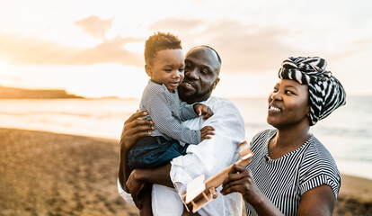 Happy African family having fun on the beach during summer vacations